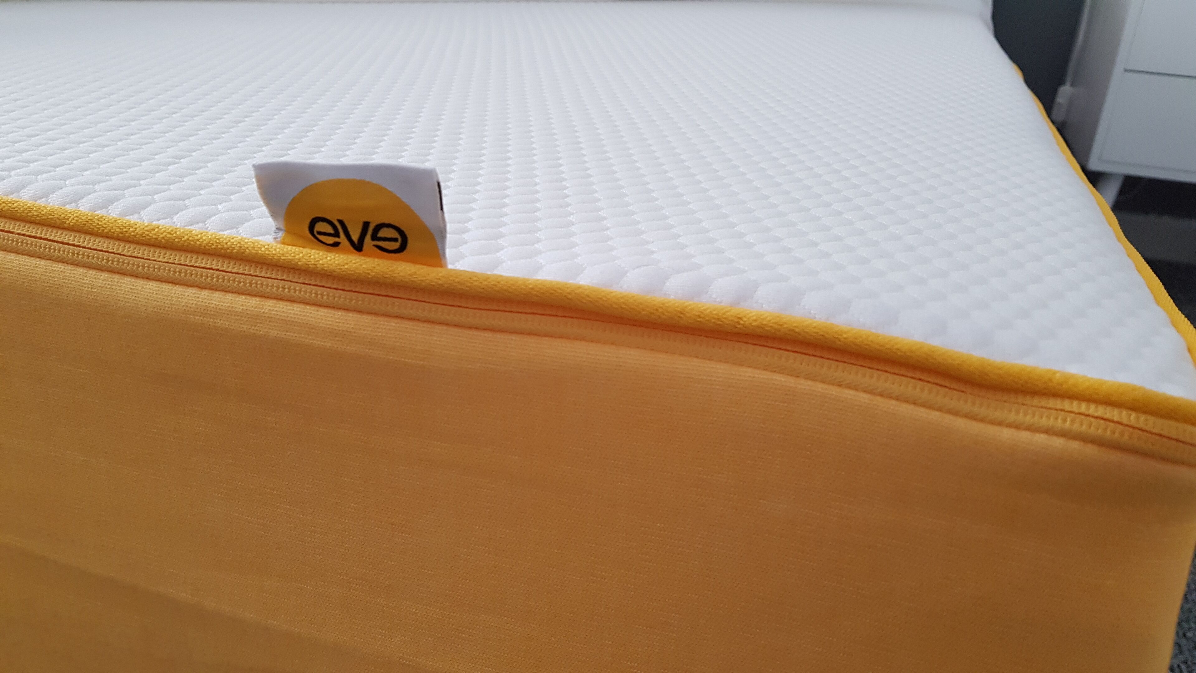 A mattress with a yellow cover and a tag labeled "eve".