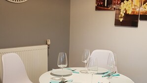 A dining area with a round table, white chairs, and a wall clock.