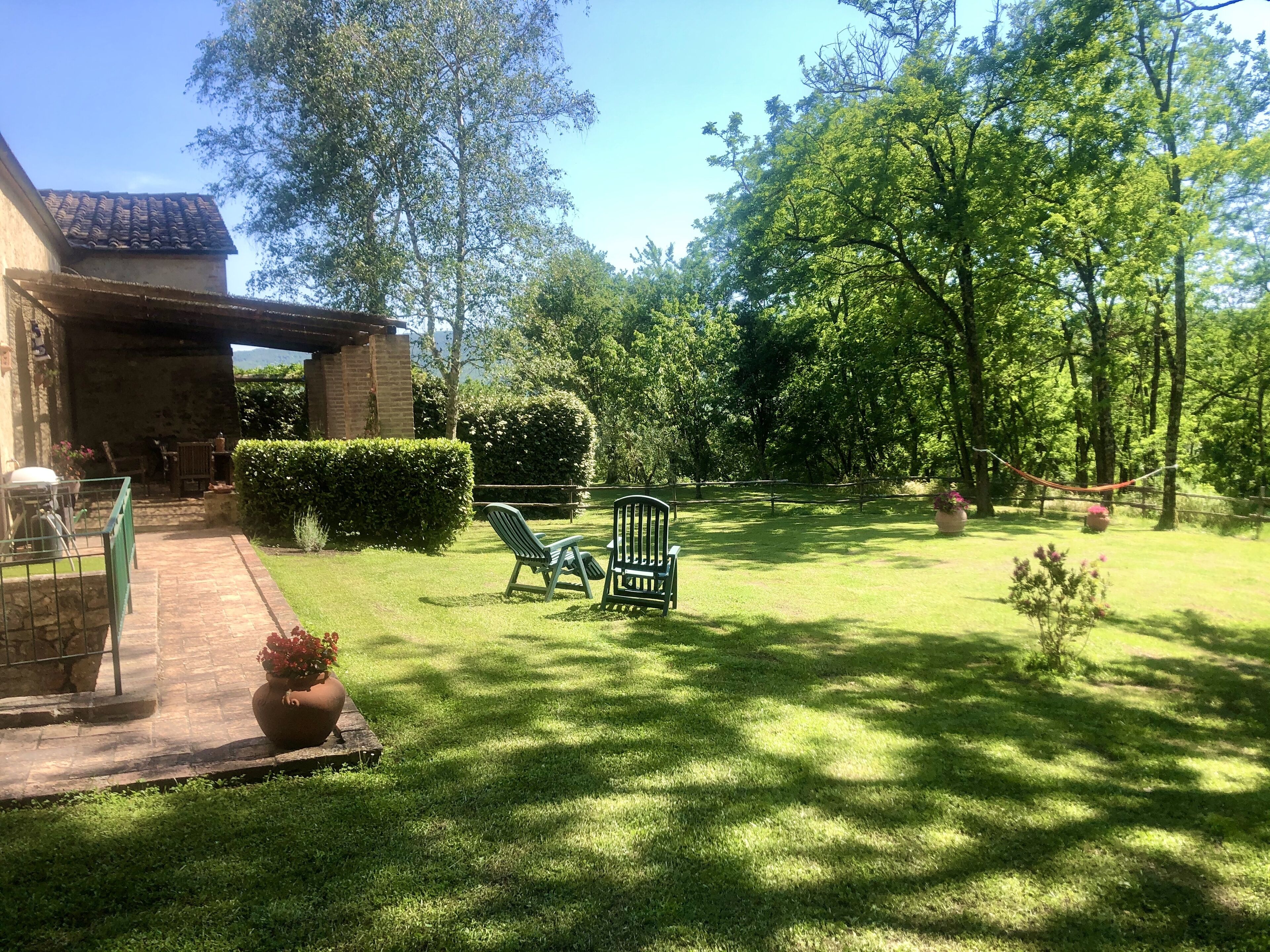 A well-maintained garden with a patio area, outdoor furniture, and a hammock.