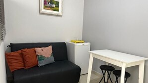 A small living area with a black sofa, two black stools, a white table, and a framed picture on the wall. - Rio Habitat - Nsa Sra Apartaments (Rio de Janeiro)