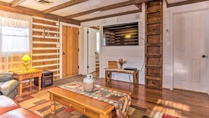 Una sala de estar acogedora con un banco de madera, una mesa de centro y una chimenea. Hay una estantería y una puerta que da a otra habitación.