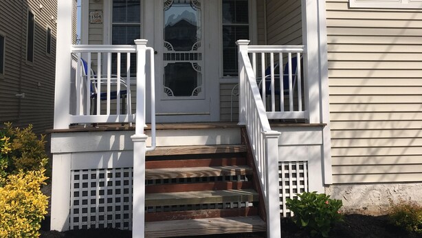 A two-story house with a front porch, a set of stairs leading to the entrance, and a mailbox.