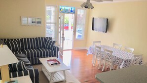 A living room with a striped sofa, a white coffee table, and a dining area with a table and chairs.