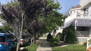 A residential street with houses on both sides, a sidewalk, and parked cars.