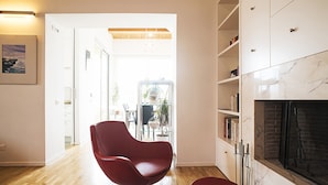 Een moderne woonkamer met een rode stoel, een open haard en een boekenkast.