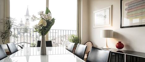 A conference room with a large table, chairs, a vase with flowers, a lamp, and framed pictures on the wall.