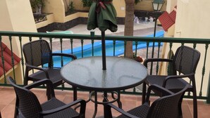 A balcony with a round table and four chairs, overlooking a swimming pool and palm trees. - Bright studio in Tenerife, with terrace, pool, internet wi-fi fiber (Adeje)