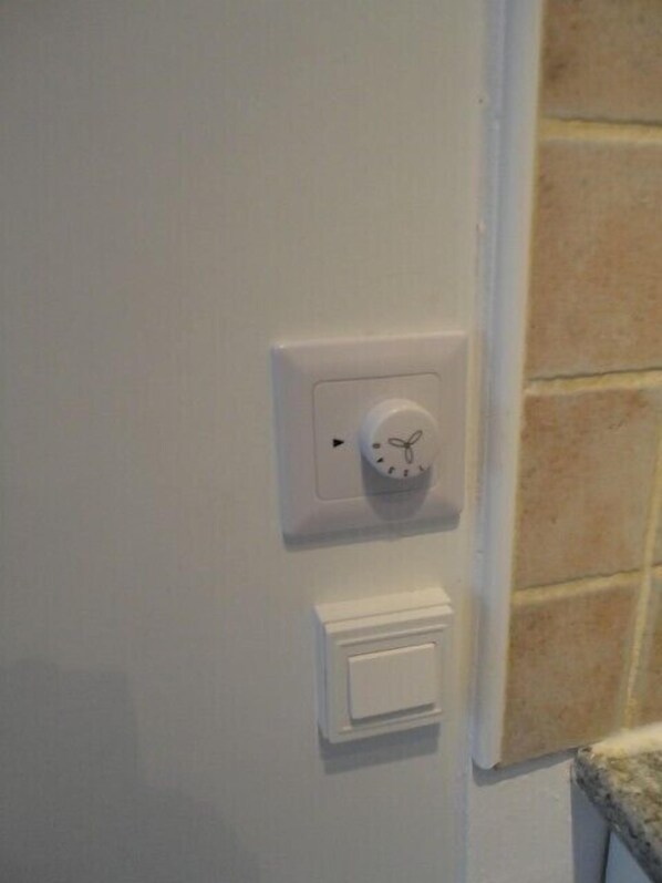 Un mur blanc avec un thermostat et un interrupteur.