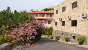 A stone building with balconies and air conditioning units. - Hotel Limeira (Cidade Velha)