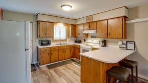 Una cocina compacta con armarios de madera, un refrigerador blanco, un microondas, una estufa y un lavamanos.