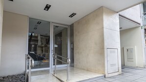 Une entrée moderne, avec une porte en verre, des rampes en métal et une zone pavée de pierres.