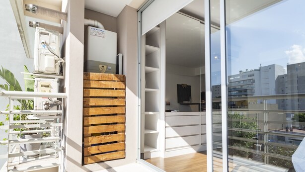 Un appartement moderne doté d’un balcon, d’une porte à lamelles en bois et offrant une vue sur le paysage urbain.