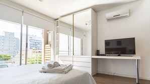 Une chambre à coucher moderne avec un lit, une télévision et une grande fenêtre.