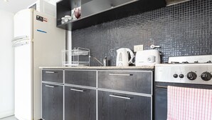 Une cuisine moderne avec des meubles en bois foncé, une cuisinière en acier inoxydable et un dosseret de carreaux noirs.