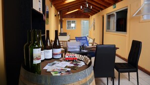 Um barril de madeira com garrafas de vinho e folhetos sobre uma mesa em um ambiente com teto alto e vigas de madeira.