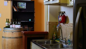 Uma cozinha com um barril de madeira, uma pia e uma geladeira.