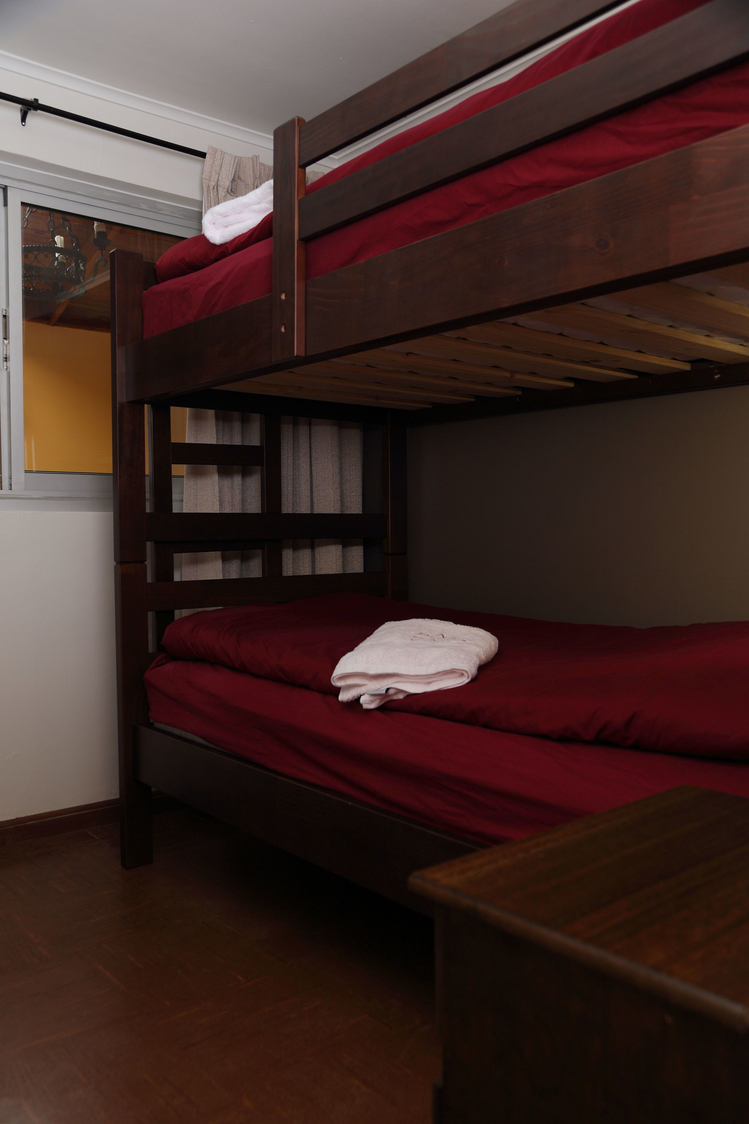 Una litera con ropa de cama roja y una toalla blanca en la cama inferior.
