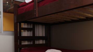 Una litera con ropa de cama roja y una toalla blanca en la cama inferior.