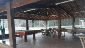 An outdoor covered area with a pool table, multiple chairs, and a dining table. - Casa Sítio Mairiporã (Mairipora)