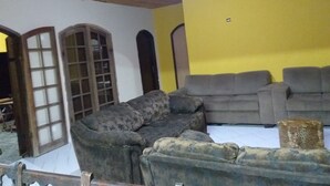 A room with a wooden ceiling, a yellow wall, and a grey sofa set. - Casa Sítio Mairiporã (Mairipora)