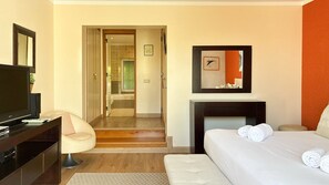 Ein Hotelzimmer mit Bett, Fernseher, Schreibtisch, Stuhl und einem durchgegangenen Tür sichtbaren Badezimmer.