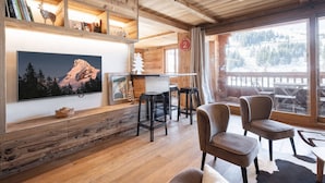 Un intérieur en bois avec un téléviseur, des étagères et une vue sur la montagne.