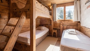 Une cabine avec des lits superposés, une petite table et une fenêtre donnant sur la forêt.