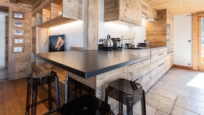Une cuisine moderne avec des meubles en bois, un îlot central, des tabourets de bar et une grande fenêtre.