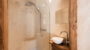Une douche avec une porte en verre, un meuble-lavabo en bois et un miroir.