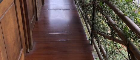 Un sendero de madera que lleva a una puerta de madera, con vistas a la vegetación y colinas al fondo.