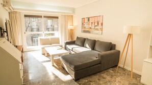 A modern living room with a grey sofa, a coffee table, and a floor lamp. There is a large window with curtains, a painting on the wall, and a small table with a lamp. - Austria apartment by Be Local Argentina (Buenos Aires)