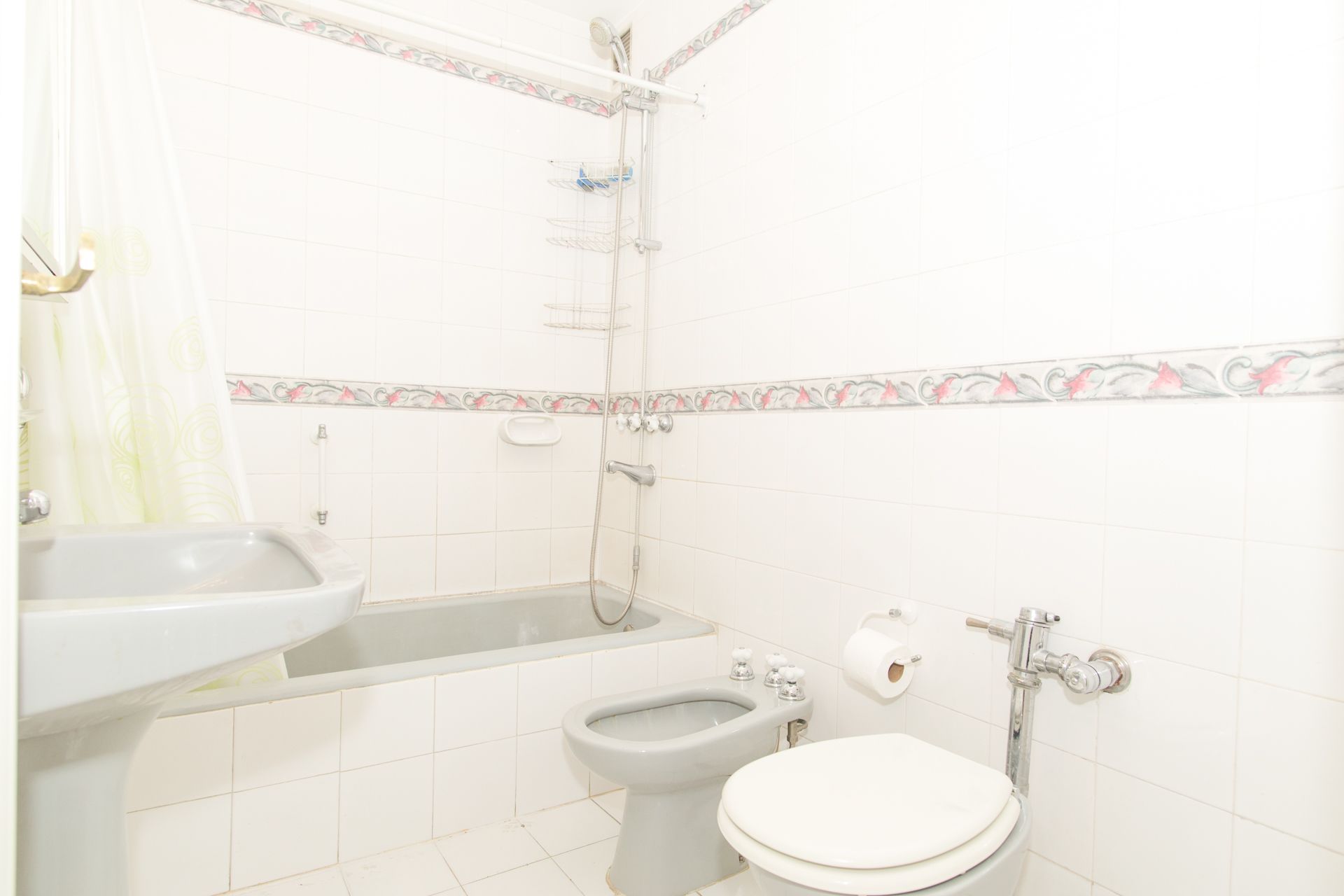 Een badkamer met een bad, een hygiëneschuiver en een toilet.