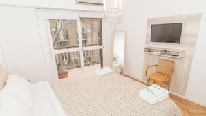 A bedroom with a bed, a chair, a TV, and a balcony with a view. - Austria apartment by Be Local Argentina (Buenos Aires)