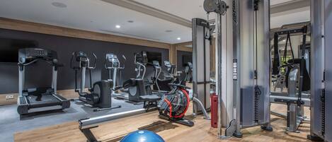 Un gimnasio con equipo de ejercicio variado, incluyendo cintas de correr, elípticas y máquinas de pesas.