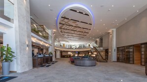 A spacious lobby with a central reception desk, multiple seating areas, and a staircase leading to upper floors. - Radisson Blu Hotel & Residences, Zakopane (Zakopane)