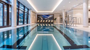 A modern indoor swimming pool with glass railings, a seating area with chairs, and a mural of a mountainous landscape. - Radisson Blu Hotel & Residences, Zakopane (Zakopane)