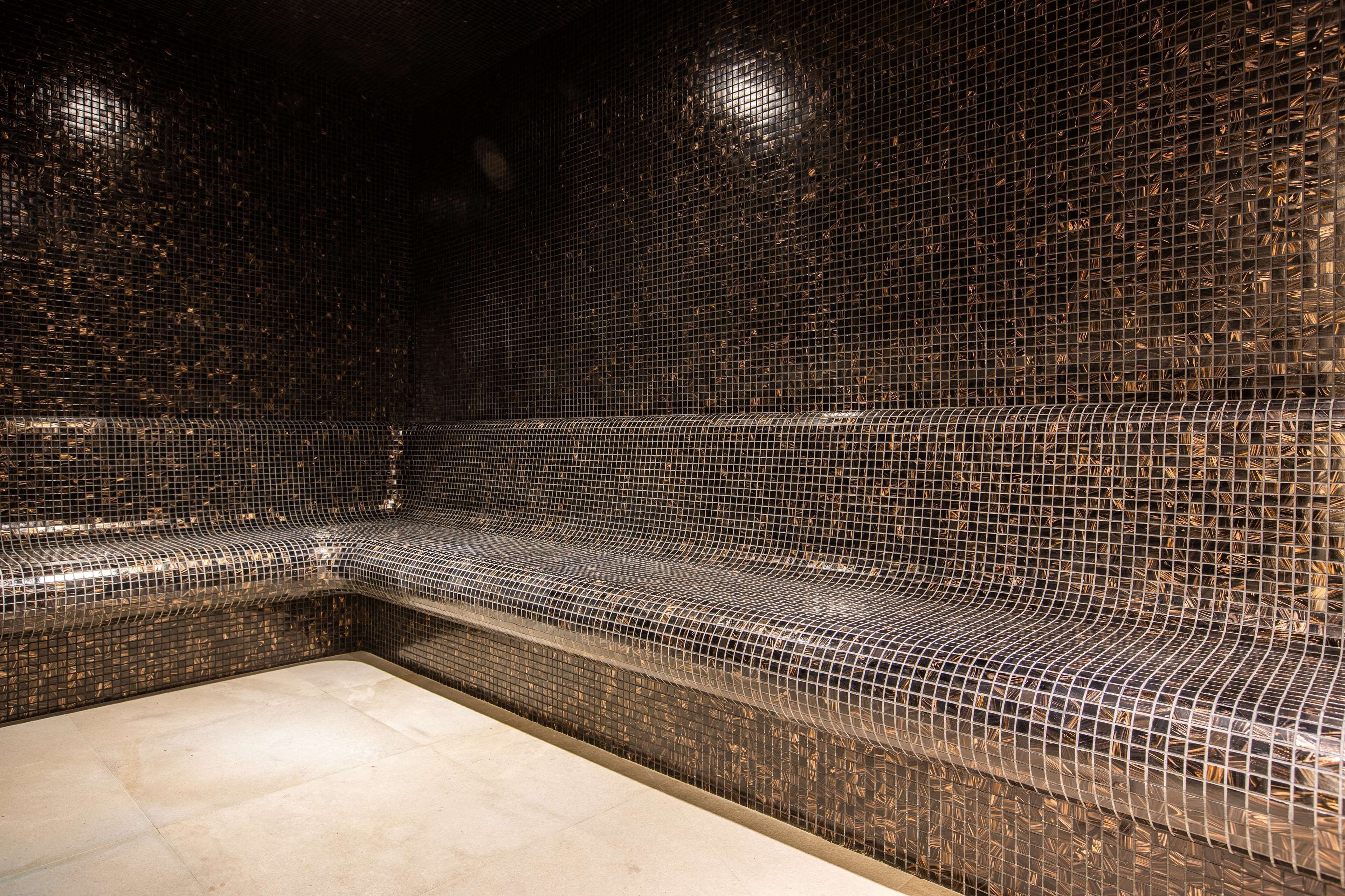A spa area with a curved bench and tiled walls.