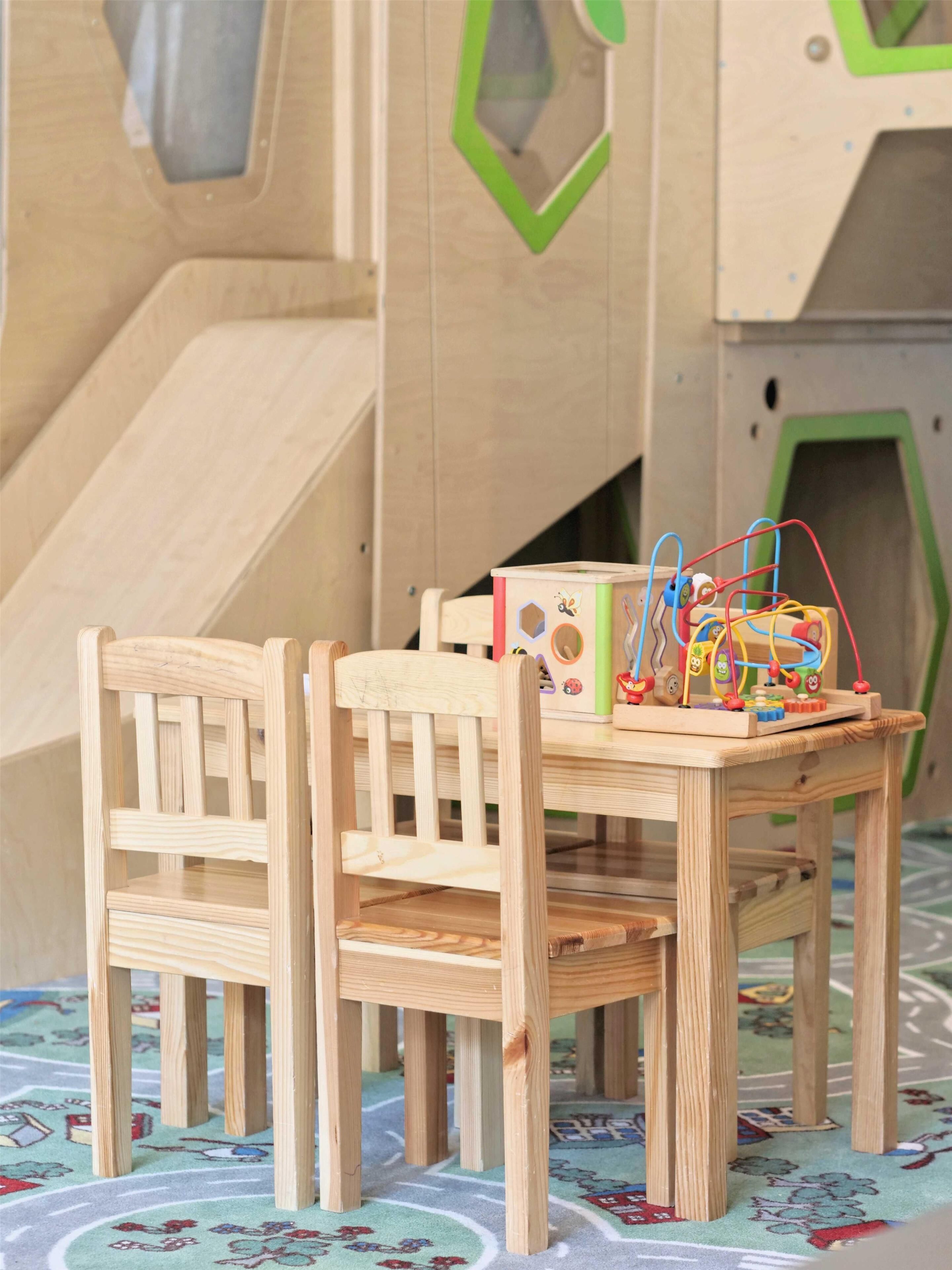 A wooden table with chairs in a room with a geometric-patterned carpet.