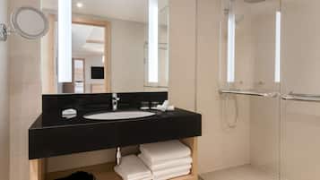 A modern bathroom with a black sink, a mirror, a glass-enclosed shower, and neatly folded white towels.