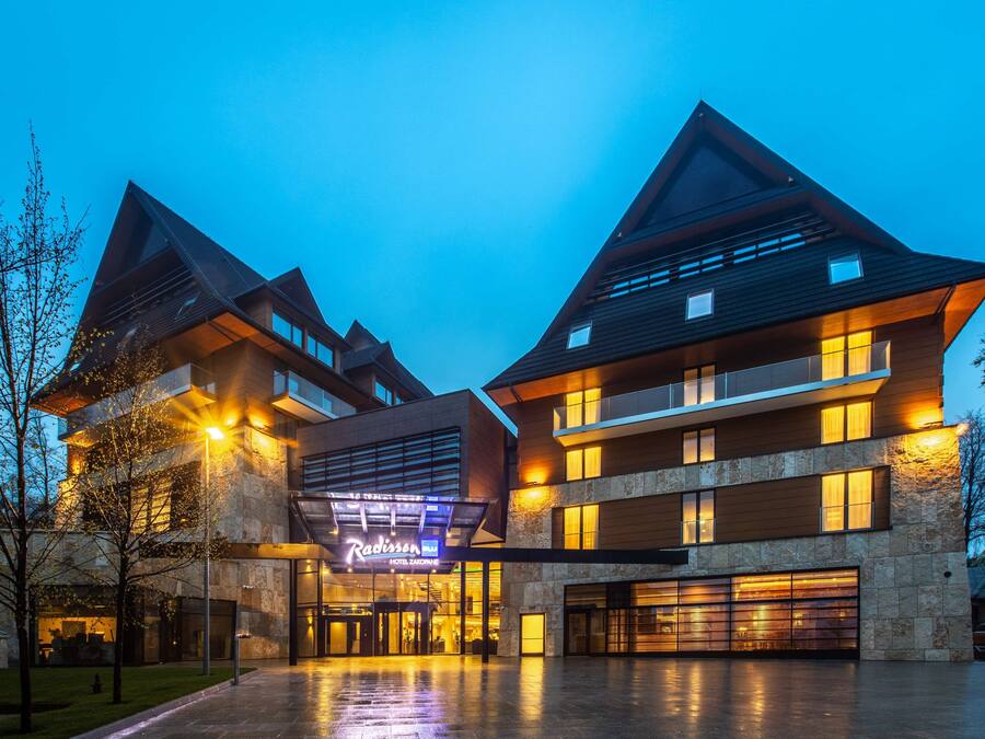 Un hôtel moderne doté d’une entrée imposante, de plusieurs étages et d’une façade bien éclairée.