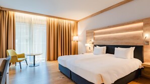 A hotel room with a large bed, a desk, a chair, and a window with curtains. - Radisson Blu Hotel & Residences, Zakopane (Zakopane)