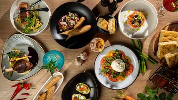 Diversos pratos em uma mesa de madeira, incluindo um prato com ovo pochê e legumes, uma salada e vários pequenos pratos com aperitivos.