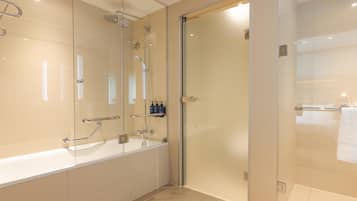 Ein modernes Badezimmer mit einer Glaskabine zur Dusche, einer freistehenden Badewanne und einer Glastür zu einem weiteren Raum.