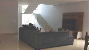 A modern living room with a grey sofa, a fireplace, and a staircase leading to another level.