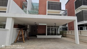 A modern building with a covered patio area, large windows, and a brick facade. - Palm Residence (George Town)