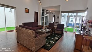 A spacious living room with a large woven sofa, a glass coffee table, and a patterned rug. - Palm Residence (George Town)