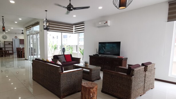 A spacious living area with wicker furniture, a television, and a ceiling fan. - Palm Residence (George Town)