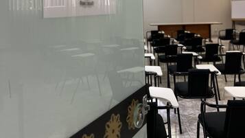 Sala de conferências com um letreiro indicando 'SALÃO DE CONVENÇÕES' e fileiras de cadeiras pretas e mesas brancas.