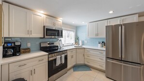 A modern kitchen with white cabinets, stainless steel appliances, and a window providing natural light. - Sea Spray 2: *Pet-friendly *Steps to the beach *Close to shops, restaurants (Anna Maria)