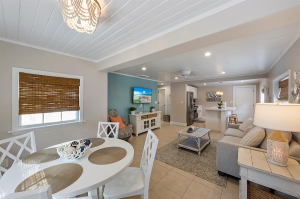 A spacious living area with a dining table, sofa, and kitchen area.